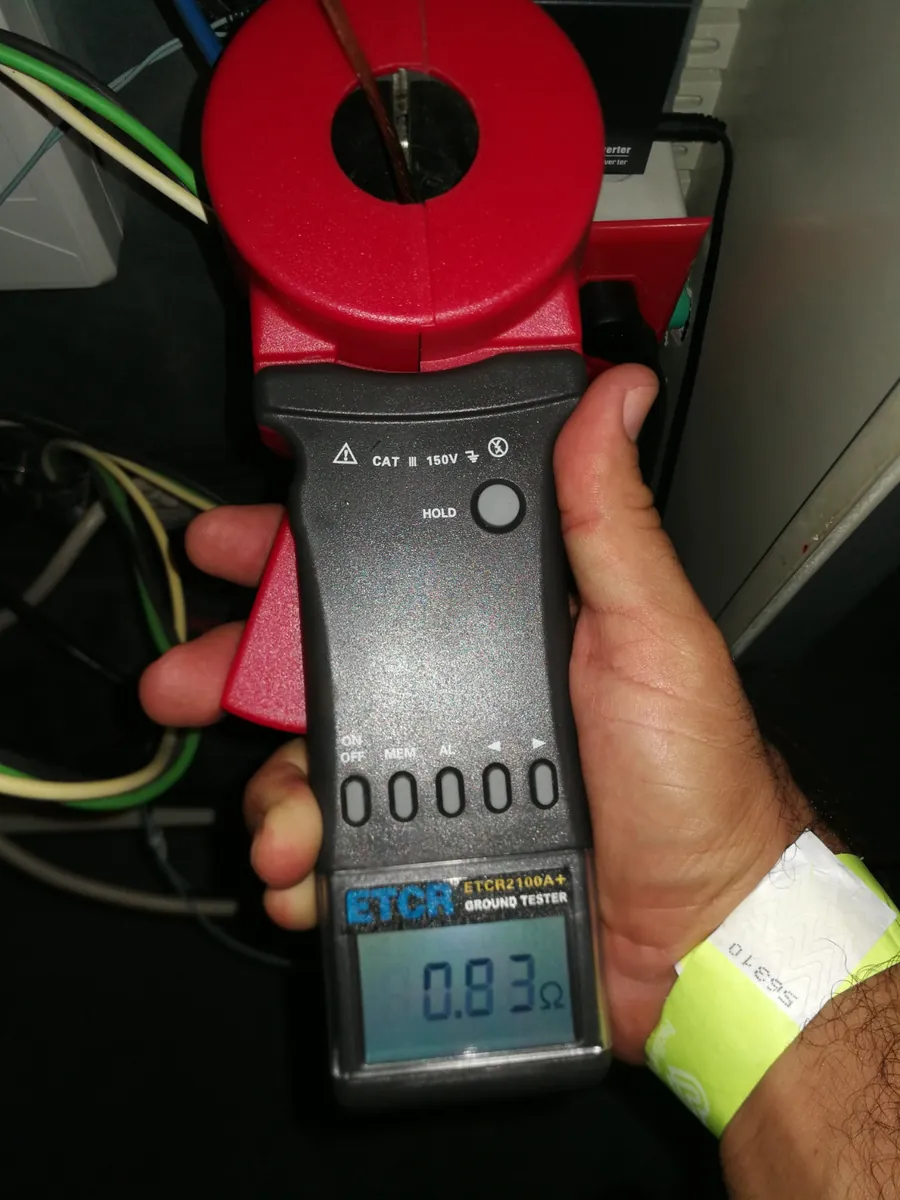 Telurómetro de pinza midiendo resistencia de puesta a tierra con lectura de 0.83 ohmios